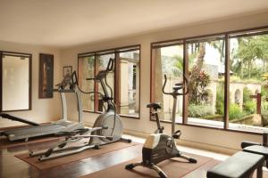 a gym with three exercise bikes and windows at The Ubud Village Resort & Spa in Ubud