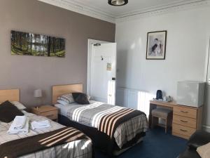 a hotel room with two beds and a desk at Armadale Guest House in Aberdeen