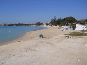 a beach with a blue trash can on the shore at Summer Beach Rooms in Fontane Bianche