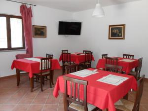 a restaurant with red tables and chairs and a flat screen tv at podere la starza in Laureana Cilento