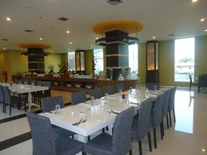 uma sala de jantar com mesas e cadeiras brancas em Hotel Olive em Tangerang