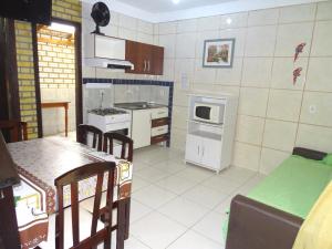 cocina con mesa y fogones horno superior en Apto Duplex Bombinhas, en Bombinhas