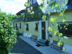 una casa amarilla con 2 bancos y un porche en Pension am Weinberg en Mesenich