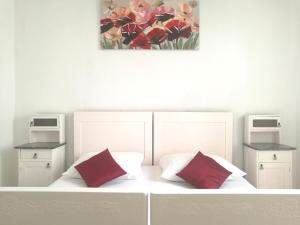 - un lit blanc avec 2 oreillers rouges et un tableau dans l'établissement Authentic Dalmatian House, à Kaštela