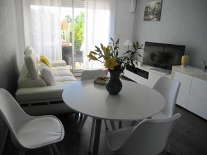 een woonkamer met een witte tafel en witte stoelen bij APPARTEMENT DUPLEX 71 m2 - 4 personnes in La Grande-Motte