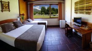 ein Hotelzimmer mit zwei Betten, einem Schreibtisch und einem Fenster in der Unterkunft Hotel Pucon Green Park in Pucón