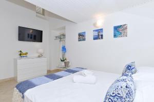 a white bedroom with a bed and a tv at La Perla Blu in Capri