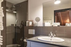 a bathroom with a sink and a shower with a mirror at Rinderberg Lodge in Zweisimmen +34 photos