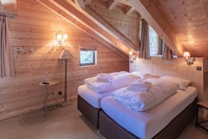 a bedroom with two beds in a log cabin at Rinderberg Lodge in Zweisimmen