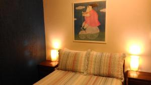 a bedroom with a bed with two lamps and a painting at Poente Guest House in Conceição da Ibitipoca