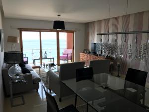 Apartamento con vistas al Mar في سيسيمبرا: غرفة معيشة مع أريكة وطاولة مع كراسي
