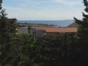 a view of houses and the ocean from the trees at Apartments MiaMaja in Novalja