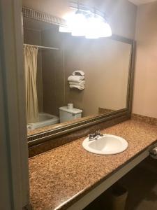 La salle de bains est pourvue d'un lavabo et d'un miroir. dans l'établissement American Inn North Kansas City, à Kansas City