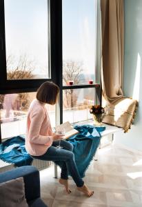 スヴェトロゴルスクにあるApartment Raushen Prestige with sea viewの本を読むテーブルに座る女性