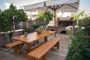 a wooden table and benches on a patio with an umbrella at Maria's Rose Garden in Lefkada