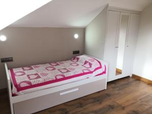 Dormitorio pequeño con cama con manta rosa en Apartamento Apega, en Ribadeo