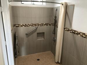 a shower with a glass door in a bathroom at American Inn & Suites LAX Airport in Inglewood