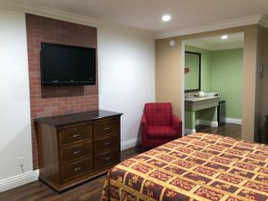 Habitación de hotel con cama y TV de pantalla plana. en American Inn & Suites LAX Airport en Inglewood