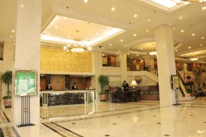um lobby de um hotel com pessoas sentadas em mesas em Qingdao Oceanwide Elite Hotel em Qingdao