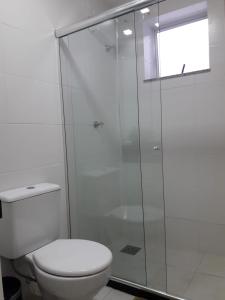 a bathroom with a toilet and a glass shower at Apto Le Bon Vivant Vista Mar in Arraial do Cabo