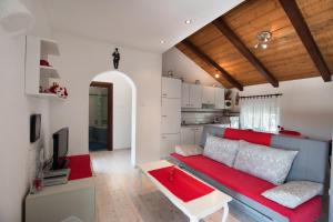 a living room with a red couch and a kitchen at Apartments Frkovic in Ledenice