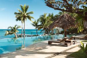 a swimming pool with palm trees and the ocean at Tokoriki Island Resort - Adults Only in Tokoriki
