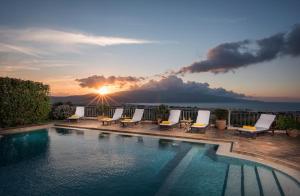 uma piscina com espreguiçadeiras e o pôr-do-sol em Caneva Luxury Villa em Tavronitis