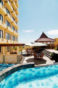 una piscina in un hotel con tavoli e ombrelloni di Pandanaran Hotel a Semarang