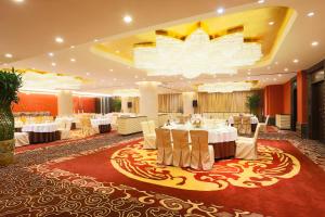 un salón de banquetes con mesas y sillas blancas y una lámpara de araña en Ritan Hotel Downtown Beijing, en Beijing