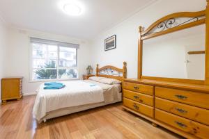 a bedroom with a bed and a dresser and a mirror at Rent Melbourne in Melbourne