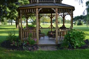 un gazebo in legno con sedie e tavoli in un parco di Sunny Isle Motel a Summerside