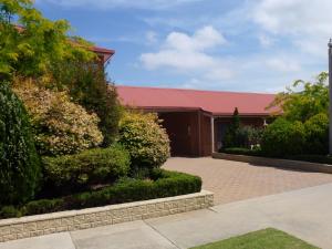 a building with a red roof and some bushes at Colonial Motor Inn Bairnsdale Golden Chain Property in Bairnsdale