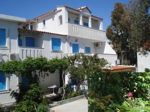 ein großes weißes Gebäude mit blauen Fenstern in der Unterkunft PELAGIA KAMPOS MARATHOKAMPOU APARTMENTs in Marathokampos