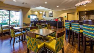 ein Restaurant mit Tischen und Stühlen und eine Bar in der Unterkunft Best Western Premier University Inn in Hattiesburg