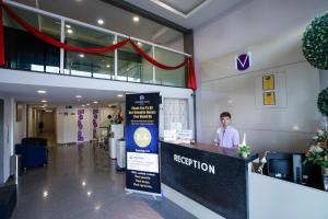 a man standing at a reception desk in a lobby at Merrinton Hotel Temerloh in Temerloh
