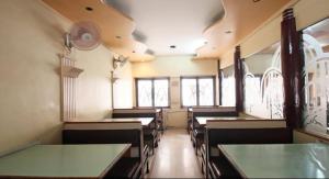 a dining room with tables and chairs and windows at Hotel Vaishali in Nashik