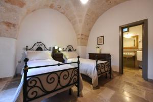 a bedroom with two beds and a bathroom with a mirror at Masseria Lamiola Piccola in Ostuni