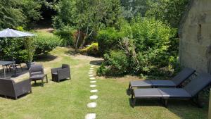 a garden with chairs and tables and an umbrella at Gîte "Le Refuge" Dans un Domaine de 7ha Au Calme in Vimoutiers +28 photos