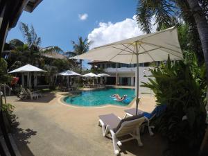 a pool with chairs and an umbrella and a person swimming at Babylon Pool Villas in Nai Harn Beach
