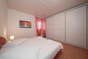 a bedroom with a large white bed and a window at Apartment Patricia in Rab