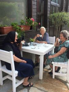 três mulheres mais velhas sentadas numa mesa branca em Hotel Bukor Shtepi Magnolia em Mandrica