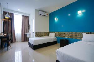 a hotel room with two beds and a blue wall at Grand FC Hotel in George Town