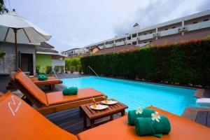 a swimming pool with two orange chairs and an umbrella at Simply Resort in Kata Beach