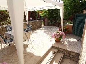 a patio with a table and chairs and an umbrella at Teo in Veli Lošinj