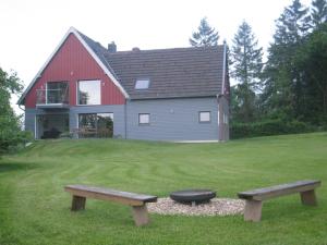 zwei Bänke vor einem roten und grauen Haus in der Unterkunft Das Burgberghaus Apartment Talaue 1.OG in Bergstein