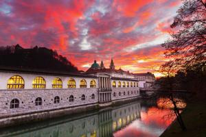 a building next to a river with a sunset at Apartment Optim in Ljubljana