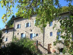 un grand bâtiment en pierre avec des arbres devant lui dans l'établissement Mas Casta Néa, à Thueyts