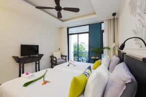 a hotel room with two beds and a ceiling fan at Maison Vy Hotel in Hoi An