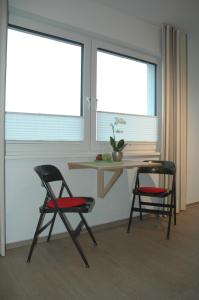two chairs and a table in a room with two windows at Apartment am Apfelgarten in Schwarmstedt