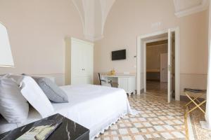 a white bedroom with a bed and a table at Palazzo Fasti in Casarano